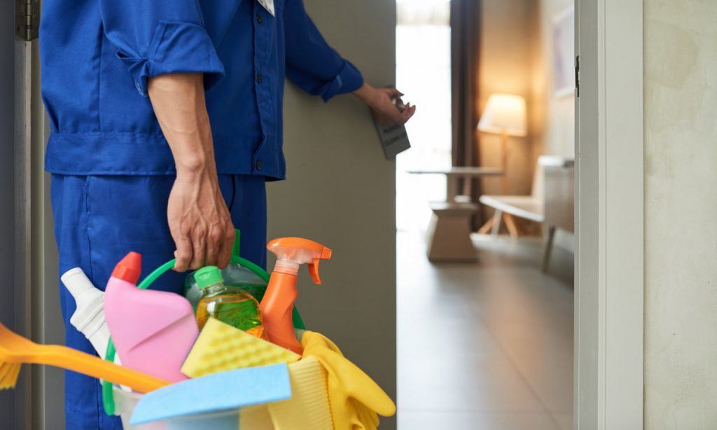 unrecognizable cleaner walking into hotel room with tools detergents min